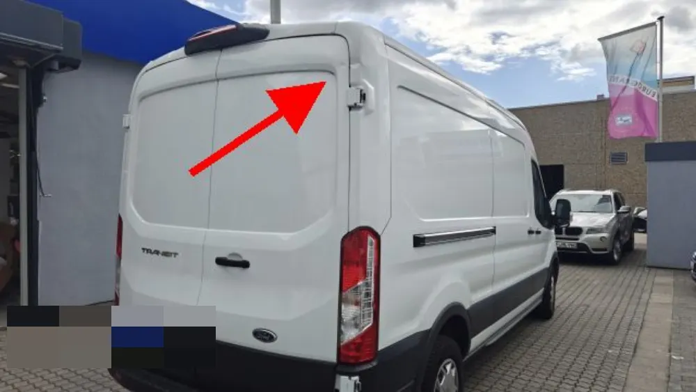 Weißer Transporter von hinten, ein roter Pfeil zeigt auf die eingedrückte Stelle in der Seitenwand, Kennzeichen verpixelt